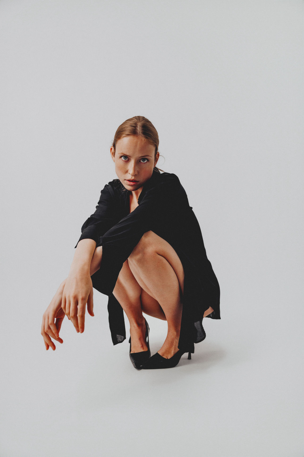 Iryna Berdnyk, studio fashion shot crouching in a black shirt